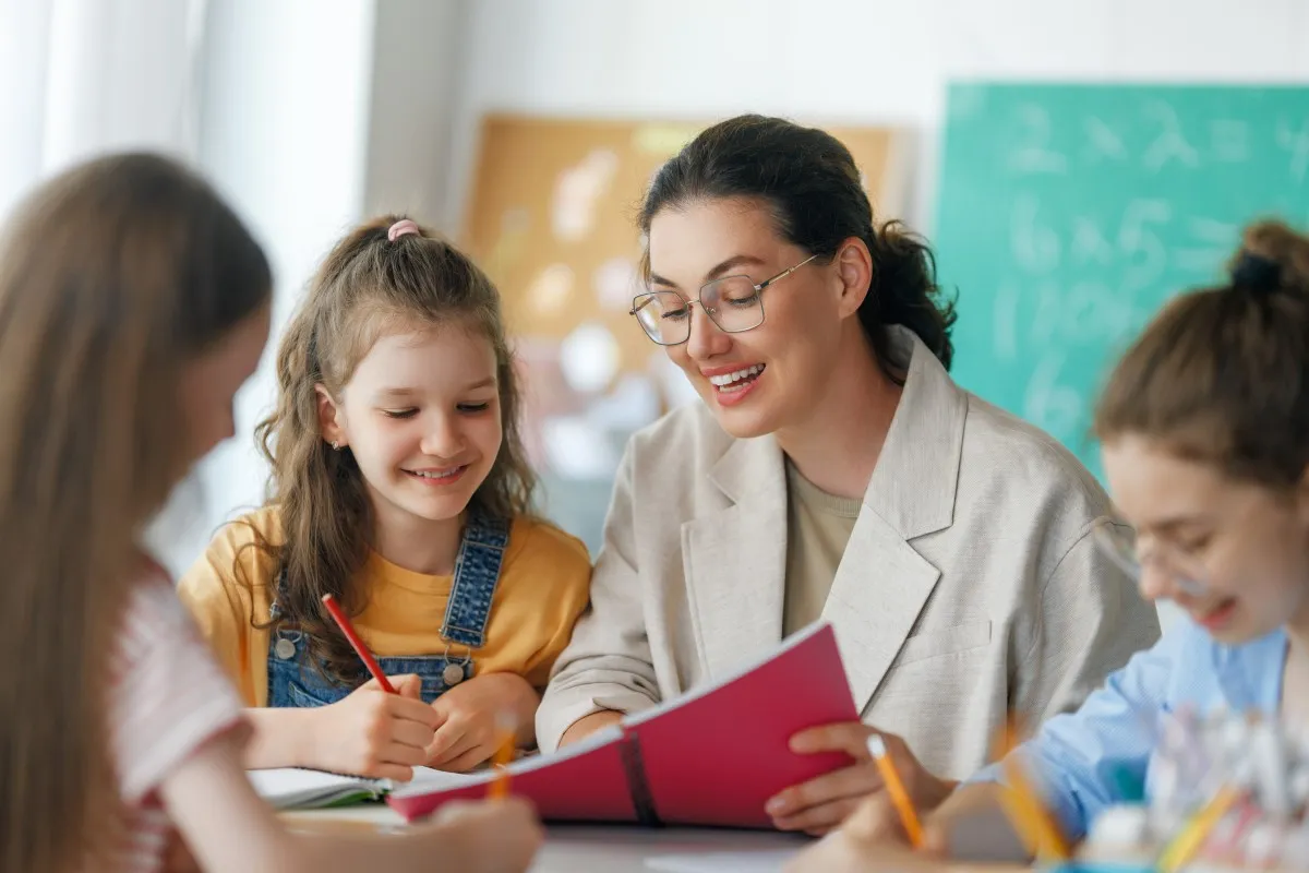 A teacher working with a small group of children at a classroom table